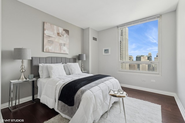 bedroom with visible vents, a view of city, baseboards, and hardwood / wood-style floors