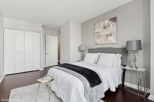 bedroom with dark wood-type flooring, a closet, and baseboards