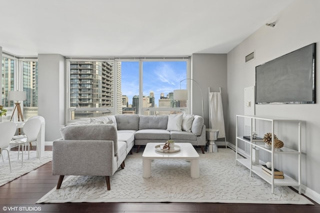 living room with a wealth of natural light, wood-type flooring, visible vents, and baseboards