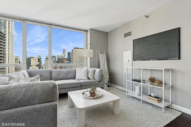 living room featuring baseboards, floor to ceiling windows, visible vents, and wood finished floors