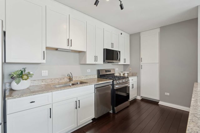 kitchen featuring stainless steel appliances, dark wood-type flooring, white cabinetry, a sink, and light stone countertops