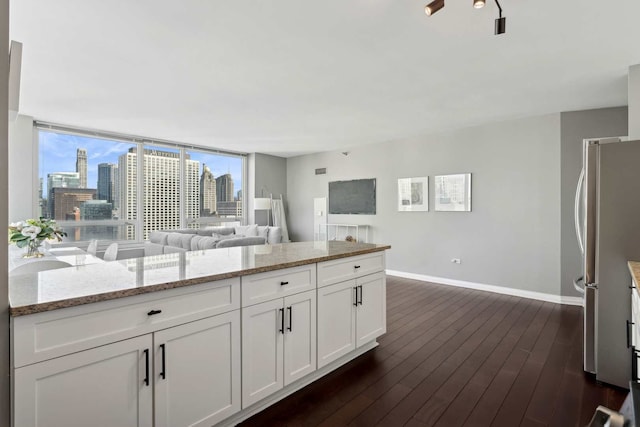 kitchen with white cabinets, light stone counters, open floor plan, freestanding refrigerator, and a city view