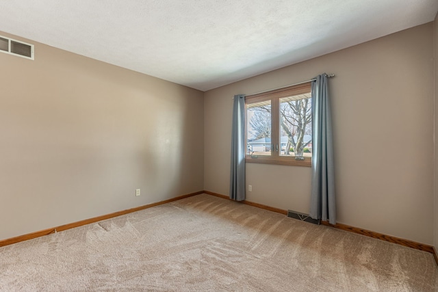 carpeted spare room with visible vents, a textured ceiling, and baseboards