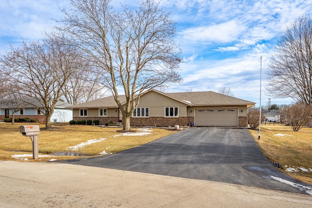 single story home with aphalt driveway, a front yard, brick siding, and an attached garage