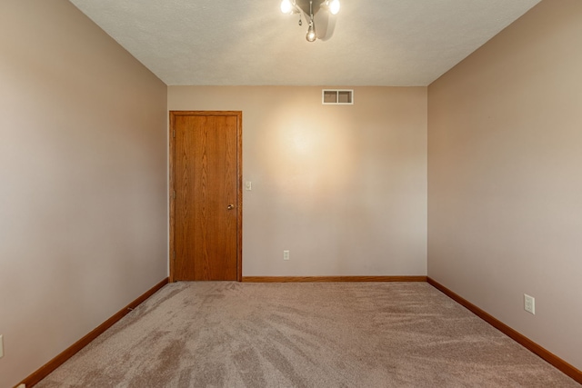 unfurnished room featuring carpet floors, baseboards, visible vents, and a textured ceiling