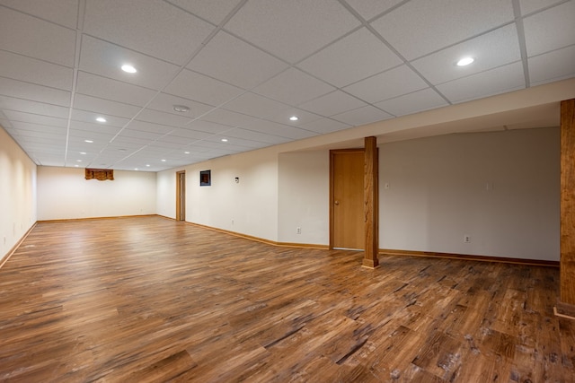 finished basement featuring baseboards, a drop ceiling, and wood finished floors