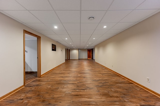 unfurnished room featuring baseboards, wood finished floors, a paneled ceiling, and recessed lighting