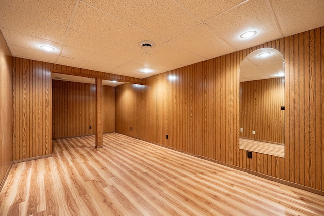 finished basement featuring wood finished floors, a paneled ceiling, and wooden walls