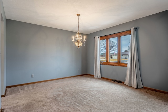 carpeted spare room featuring baseboards, visible vents, and a chandelier