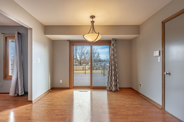 unfurnished dining area with visible vents, light wood-style flooring, and baseboards