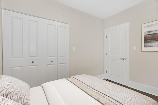 bedroom with ornamental molding, a closet, baseboards, and wood finished floors