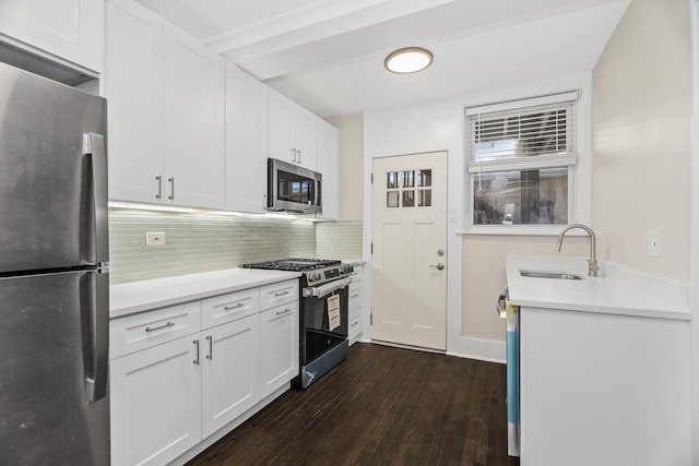 kitchen featuring appliances with stainless steel finishes, light countertops, white cabinetry, and a sink