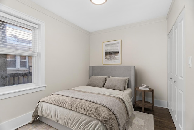 bedroom featuring a closet, crown molding, baseboards, and wood finished floors