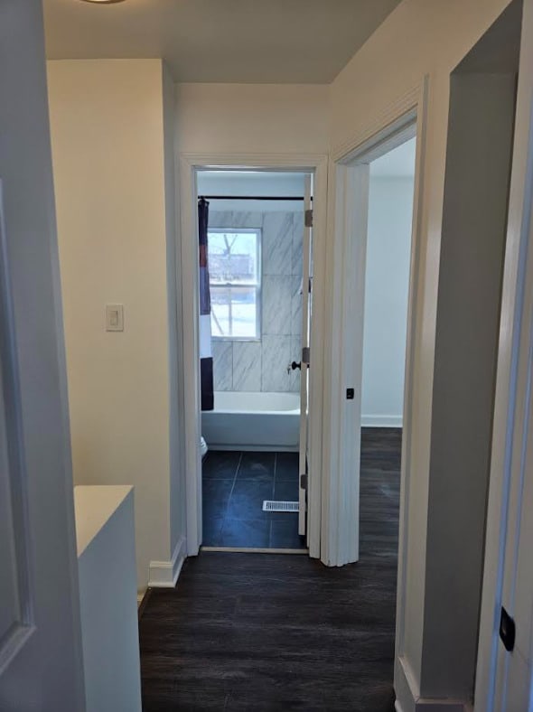 hallway with dark wood-style floors and baseboards