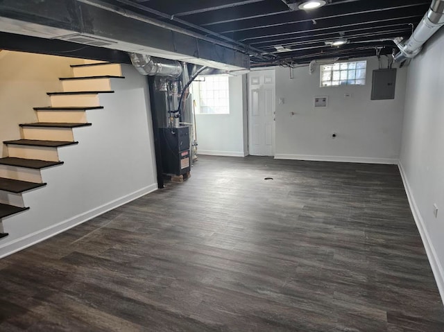 below grade area featuring baseboards, stairway, electric panel, heating unit, and dark wood finished floors