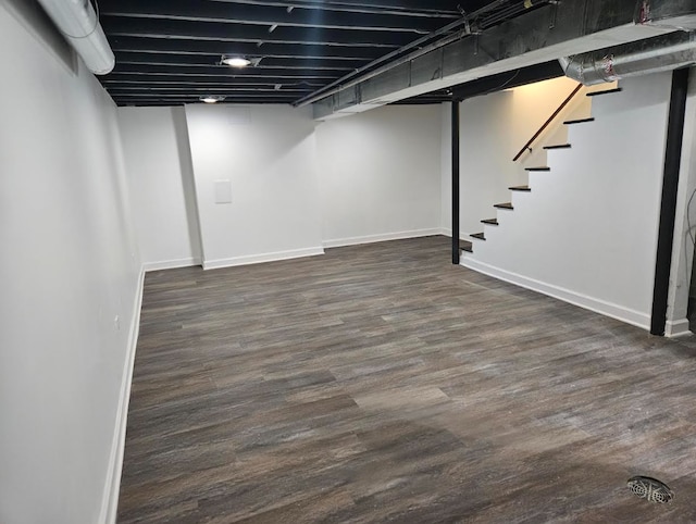 finished below grade area with stairs, dark wood-style flooring, and baseboards