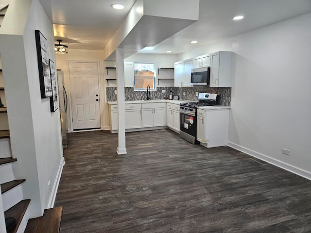 kitchen featuring white cabinets, stainless steel appliances, light countertops, open shelves, and backsplash