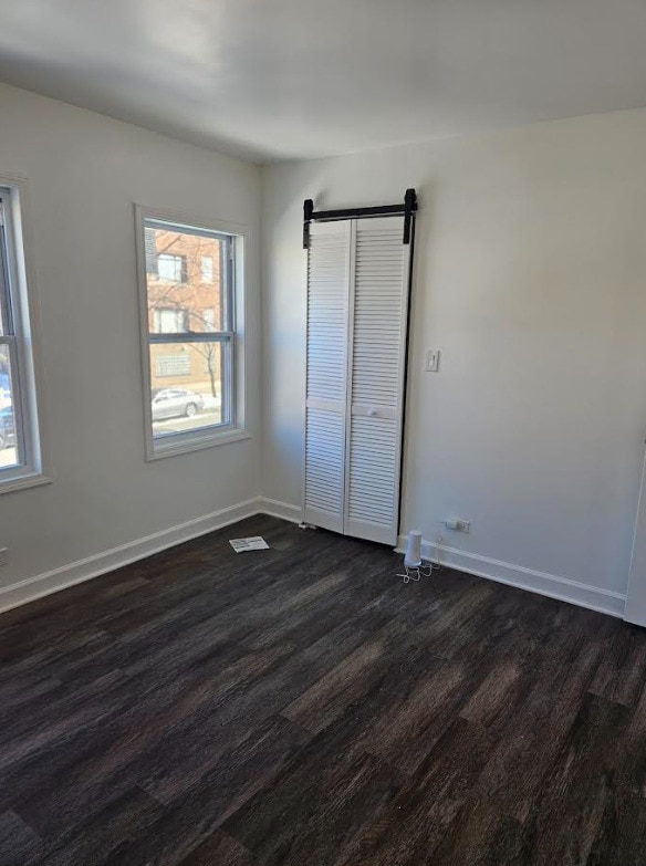 unfurnished bedroom with dark wood finished floors and baseboards