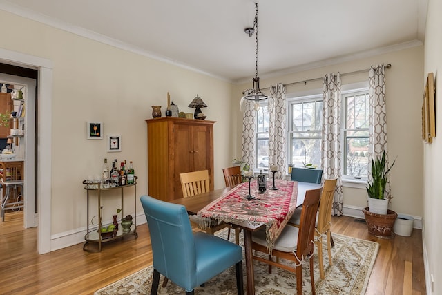 dining room with baseboards, crown molding, and wood finished floors