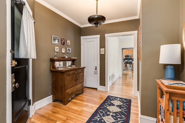 interior space with light wood-style floors, visible vents, crown molding, and baseboards