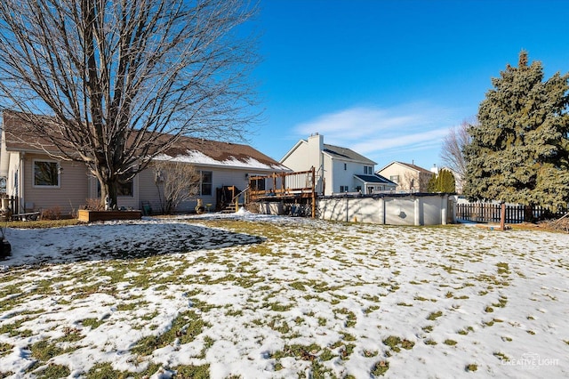 snow covered property with a covered pool and a wooden deck