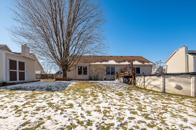 snow covered rear of property featuring fence