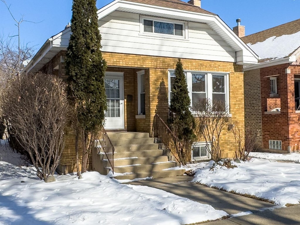 view of front of home featuring brick siding and a chimney