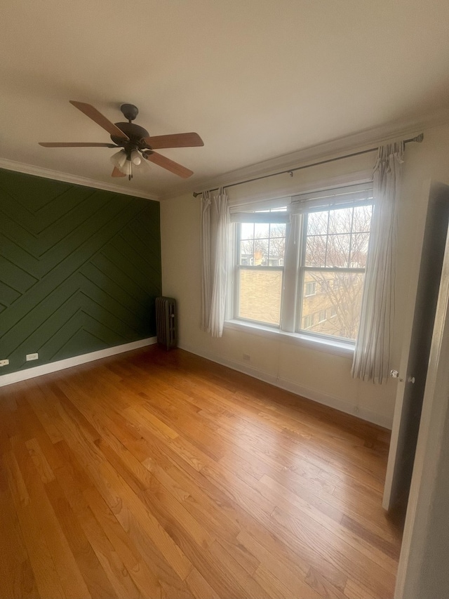 empty room with ornamental molding, radiator heating unit, and light wood-style flooring