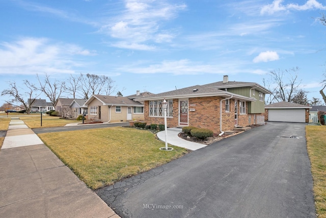 view of front of house featuring an outbuilding, a front lawn, a detached garage, and brick siding