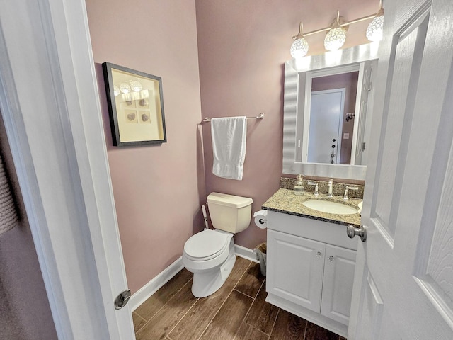 bathroom with wood tiled floor, baseboards, vanity, and toilet