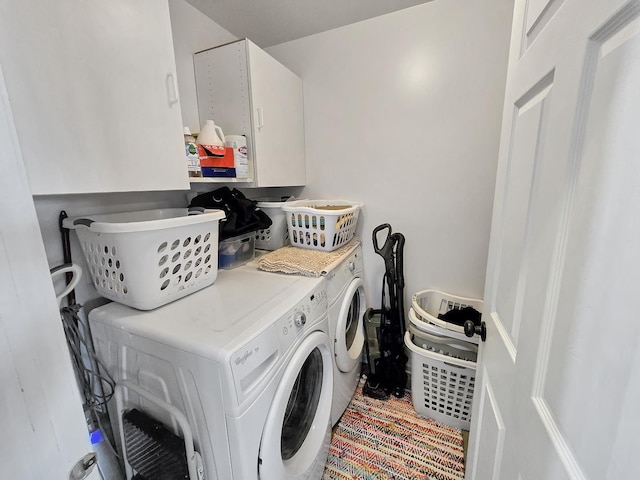 clothes washing area with washing machine and dryer and cabinet space