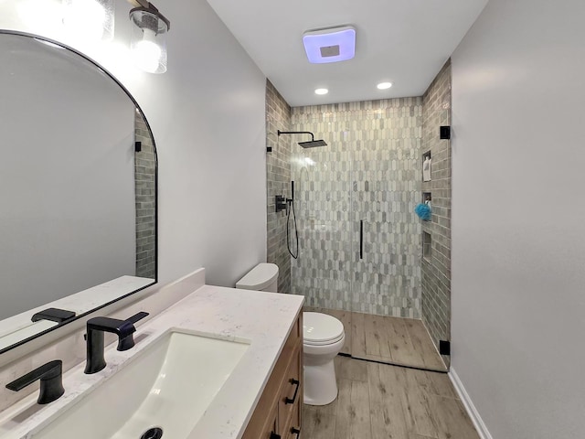 full bath with a stall shower, toilet, wood finished floors, vanity, and recessed lighting