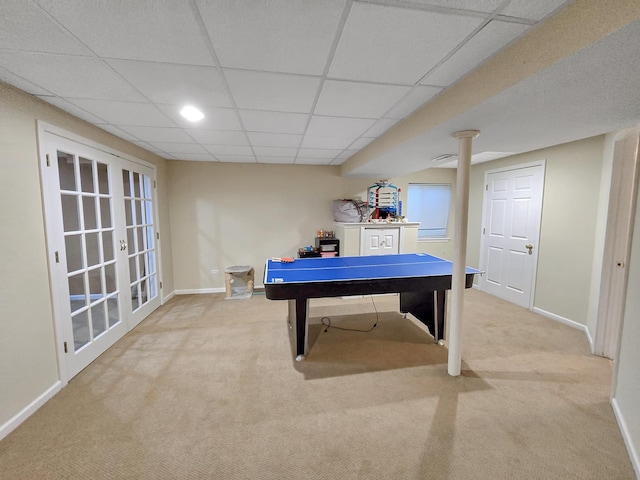 recreation room featuring a paneled ceiling, french doors, light carpet, and baseboards