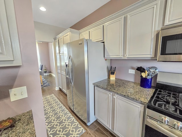 kitchen with wood finish floors, stainless steel appliances, recessed lighting, stone countertops, and white cabinetry