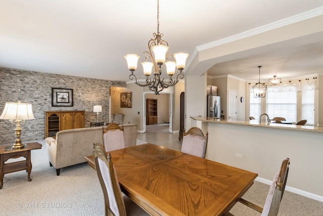 dining room featuring arched walkways, an accent wall, light carpet, and an inviting chandelier