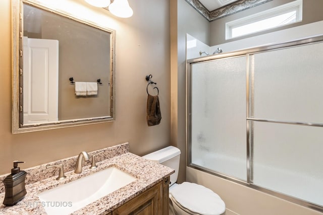 full bathroom with combined bath / shower with glass door, vanity, and toilet