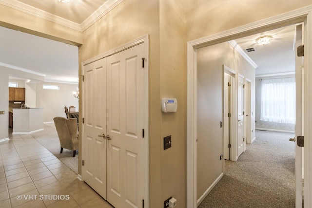 corridor featuring light tile patterned floors, baseboards, visible vents, and crown molding