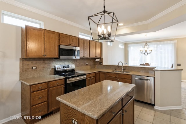 kitchen with brown cabinetry, a peninsula, a sink, stainless steel appliances, and a notable chandelier