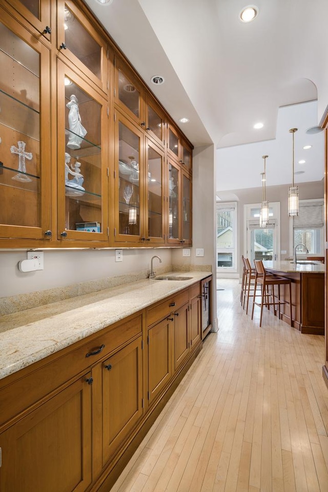 bar featuring recessed lighting, decorative light fixtures, a sink, and light wood-style flooring