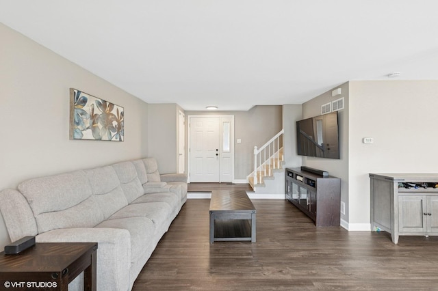 living room featuring dark wood-style flooring, visible vents, baseboards, and stairs