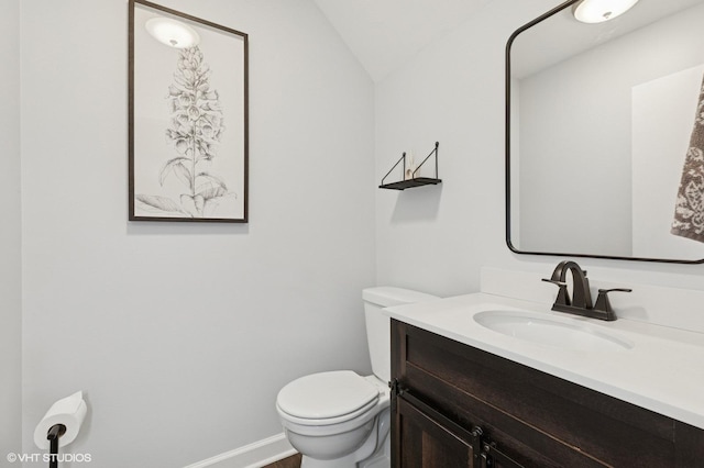 bathroom with toilet, baseboards, vaulted ceiling, and vanity