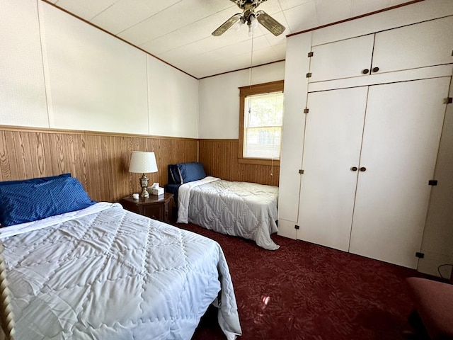 carpeted bedroom featuring vaulted ceiling, wainscoting, a ceiling fan, and wooden walls