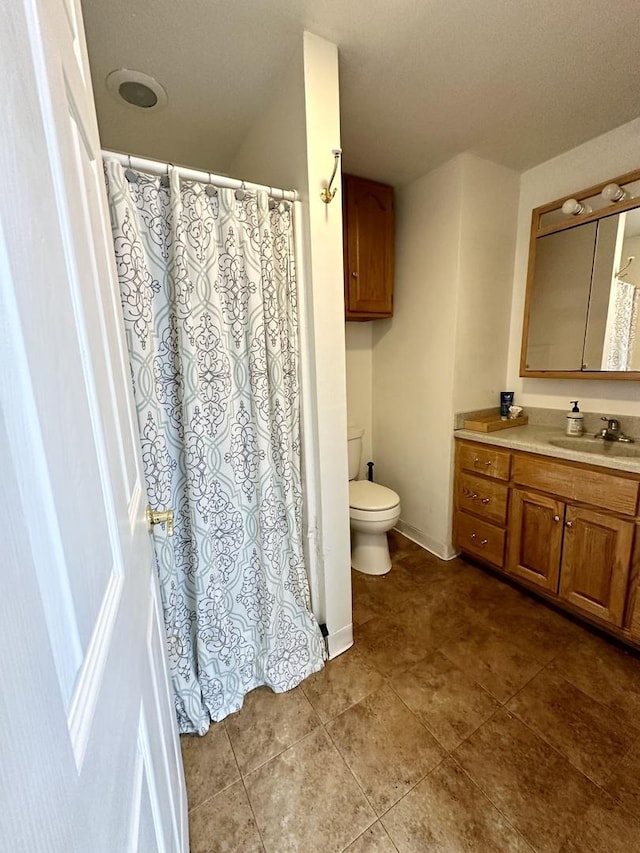 bathroom with tile patterned flooring, baseboards, vanity, and toilet