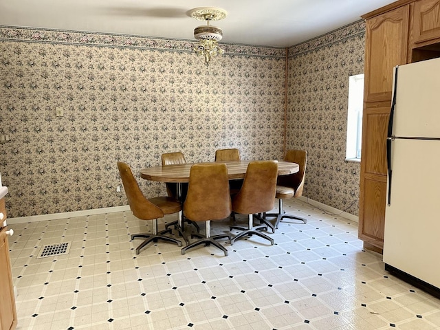 dining room with light floors, visible vents, baseboards, and wallpapered walls