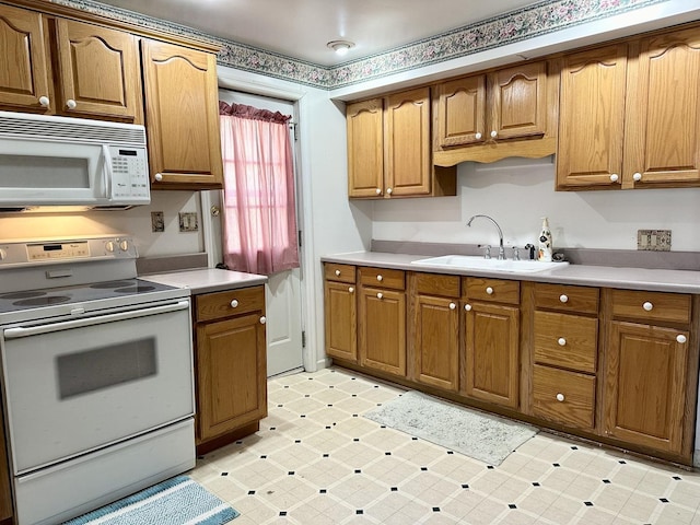 kitchen featuring light countertops, white appliances, light floors, and a sink