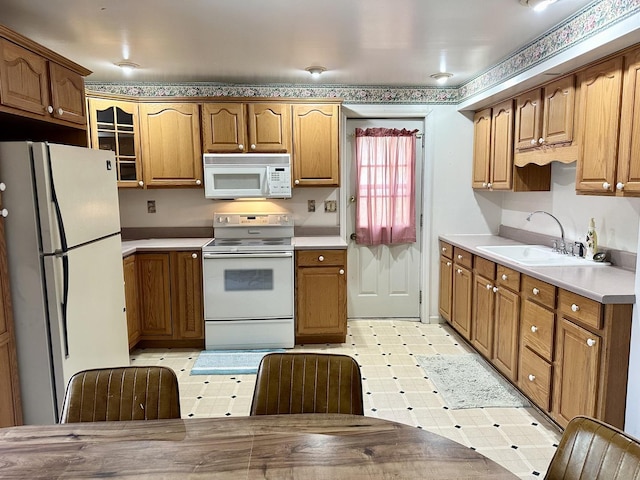 kitchen with light floors, light countertops, glass insert cabinets, a sink, and white appliances