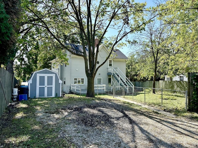 rear view of house with an outbuilding, a fenced backyard, a chimney, and a storage unit