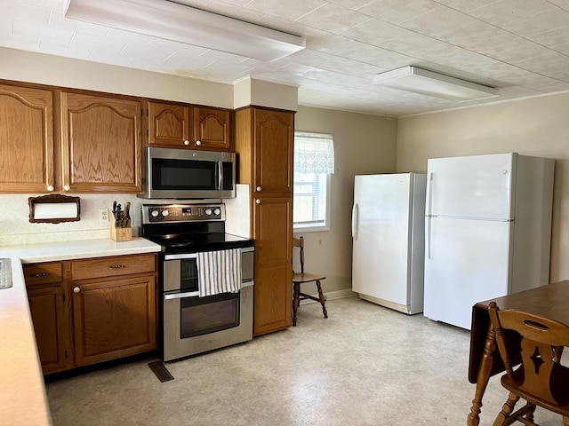 kitchen featuring appliances with stainless steel finishes, brown cabinetry, light countertops, and light floors