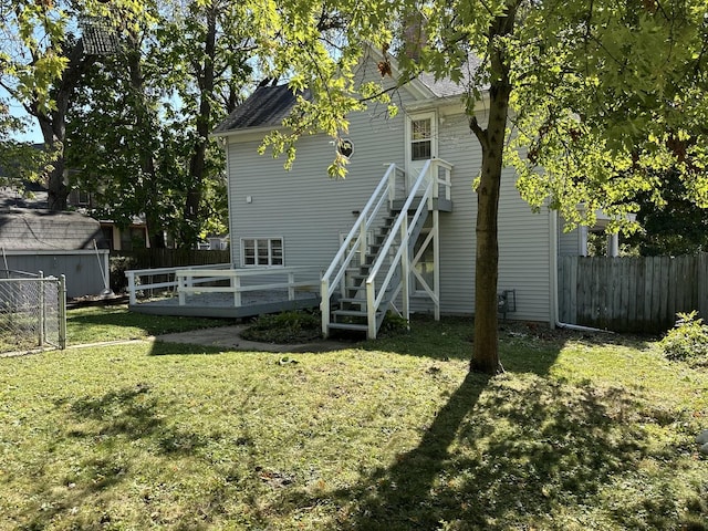 back of property with a yard, stairway, a wooden deck, and fence