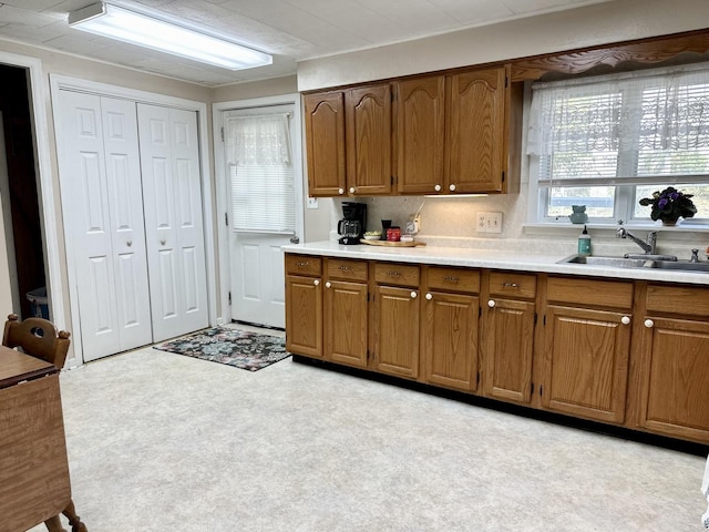 kitchen featuring brown cabinets, light countertops, a sink, and light floors